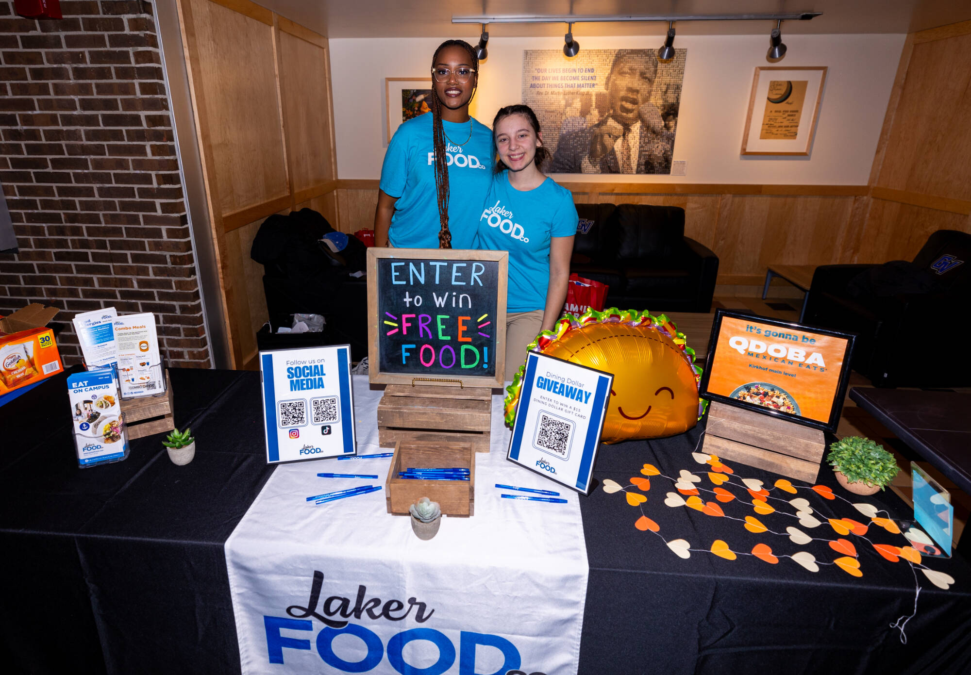 two individuals stand behind a table with a sign that says Laker Food Co.
